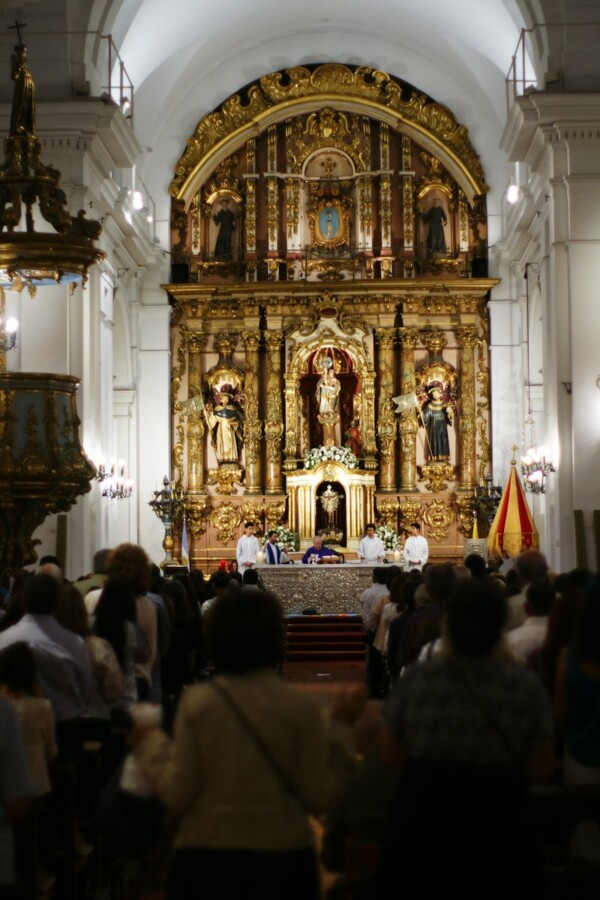 Intricate altar in a Buenos Aires church with attendees during a religious ceremony.