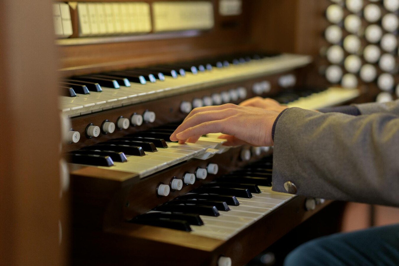 Musician's hands skillfully playing a classical church organ keys in close-up view.